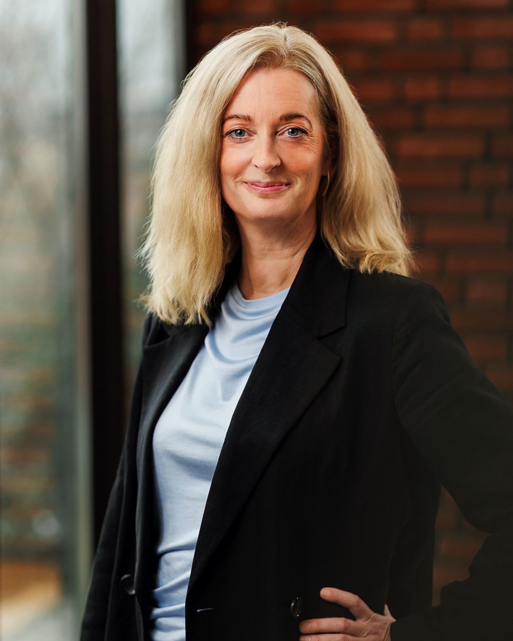 Dr. Petra Sundström steht in einem schwarzen Blazer vor einer Ziegelwand.