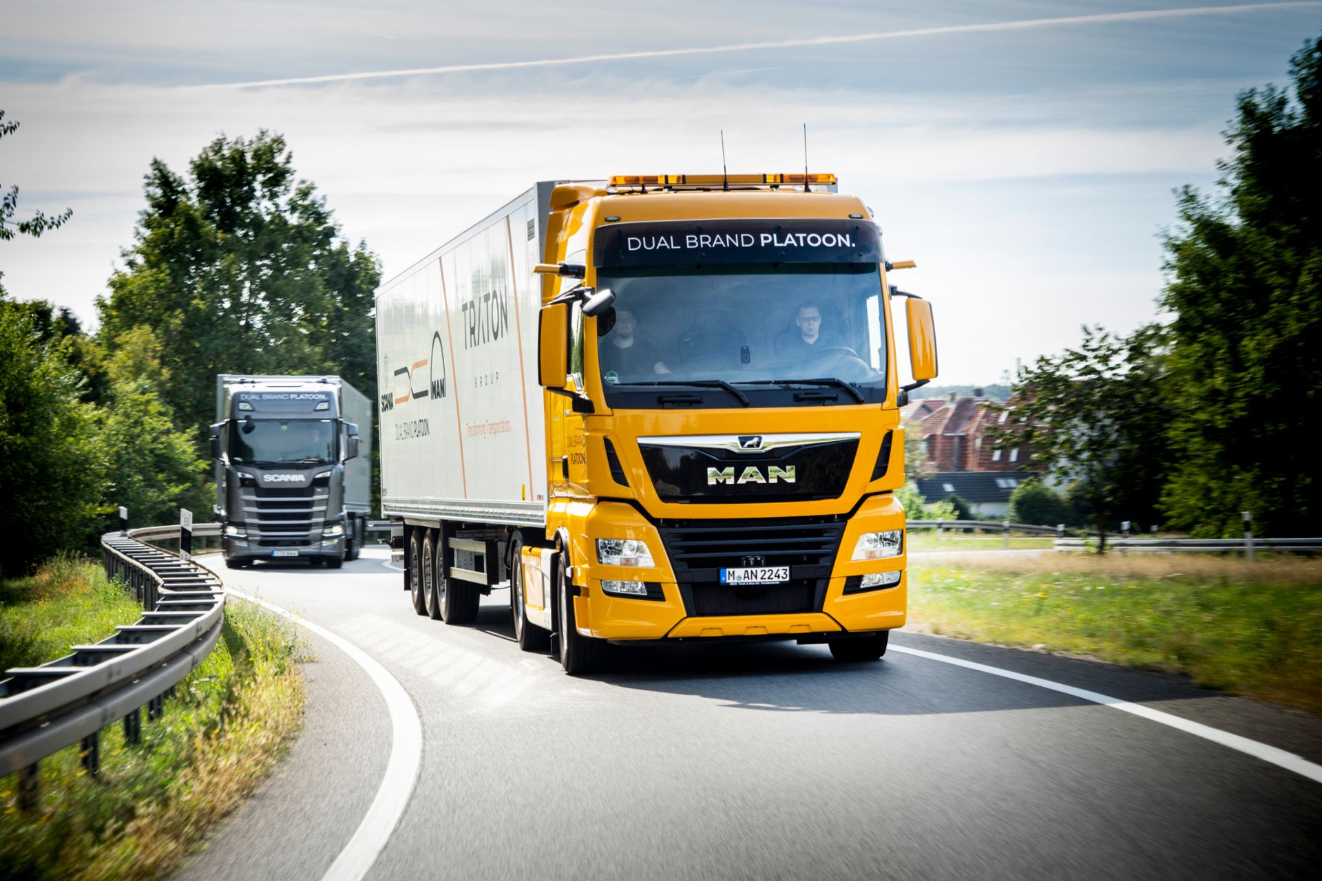 Dual Brand Platoon by MAN and Scania Orange truck with MAN brand drives on highway